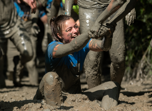 Woman covered in mud: Getting mud out of your clothes after an obstacle run.
