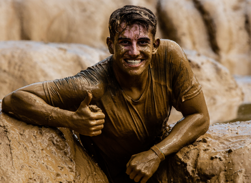 Jongen die compleet onder de modder zit tijdens de obstacle run: modder uit kleding krijgen spijkerbroek stoffen schoenen moddervlekken uit kleding